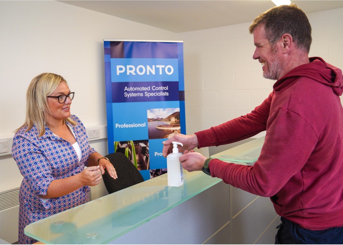Staff and client using hand sanitiser at Pronto Automation office